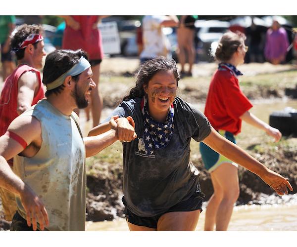 学生 laughing as they make their way through the mud during oozeball.